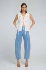 A woman wearing light blue denim jeans and white lace top