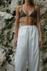 Close-up of the Coconut Pants in Coconut Ivory showing the elasticated waistband, adjustable drawstring and large side pockets. Styled with swwimwear as lightweight beach pants.