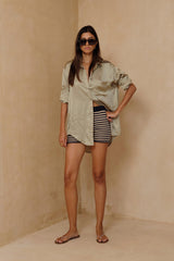 Model wearing knit shorts and a satin shirt for a resort-style outfit.