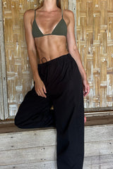 Model wearing the black Coconut Pants by lilya as beach pants over a bikini.