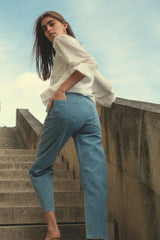 A woman walking on stairs wearing a long sleeve white lace blouse