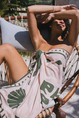 a woman laying down wearing green and pink sarong