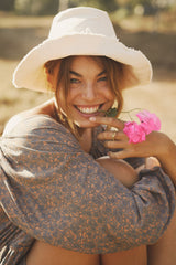 A woman wearing a bucket hat by cove. island essentials