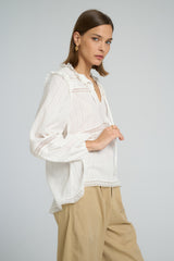 Boho-style white lace top featuring tie neck design and relaxed long sleeve fit.