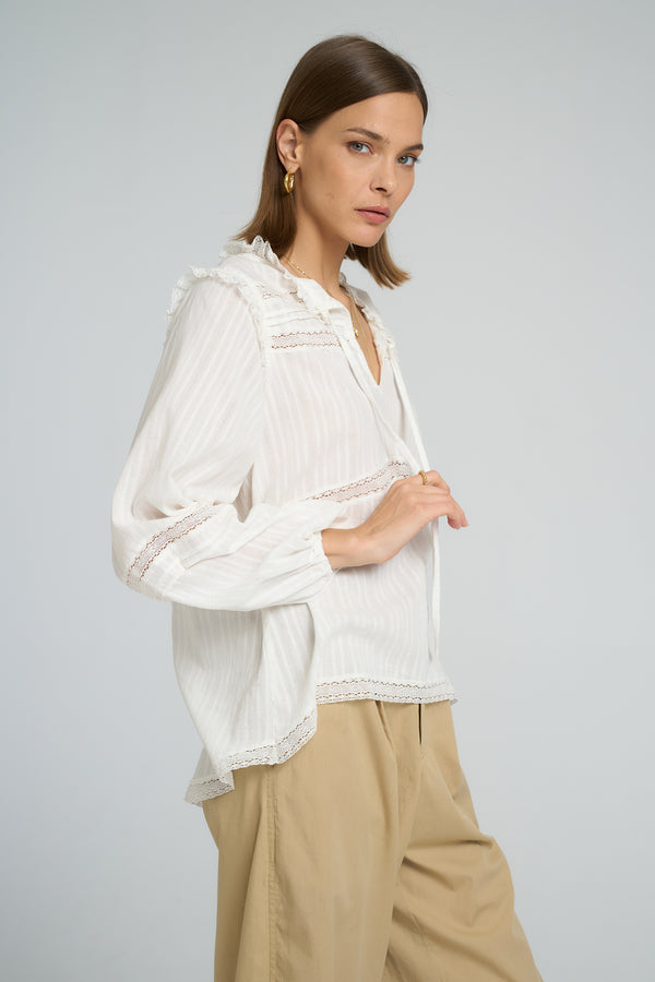 Boho-style white lace top featuring tie neck design and relaxed long sleeve fit.