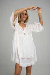 A model showing detail of the lace of a white cotton boho mini dress by Lilya