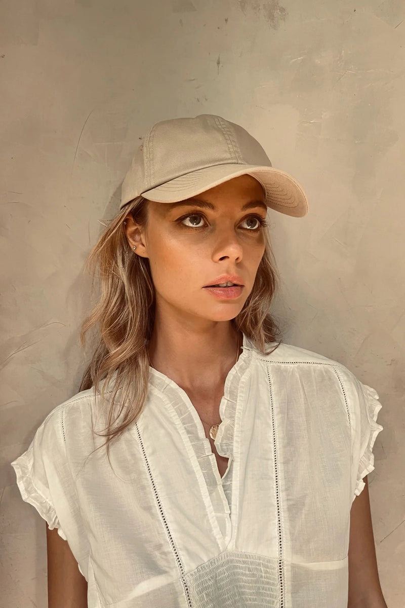 A model wearing Cove. caps in sand colour