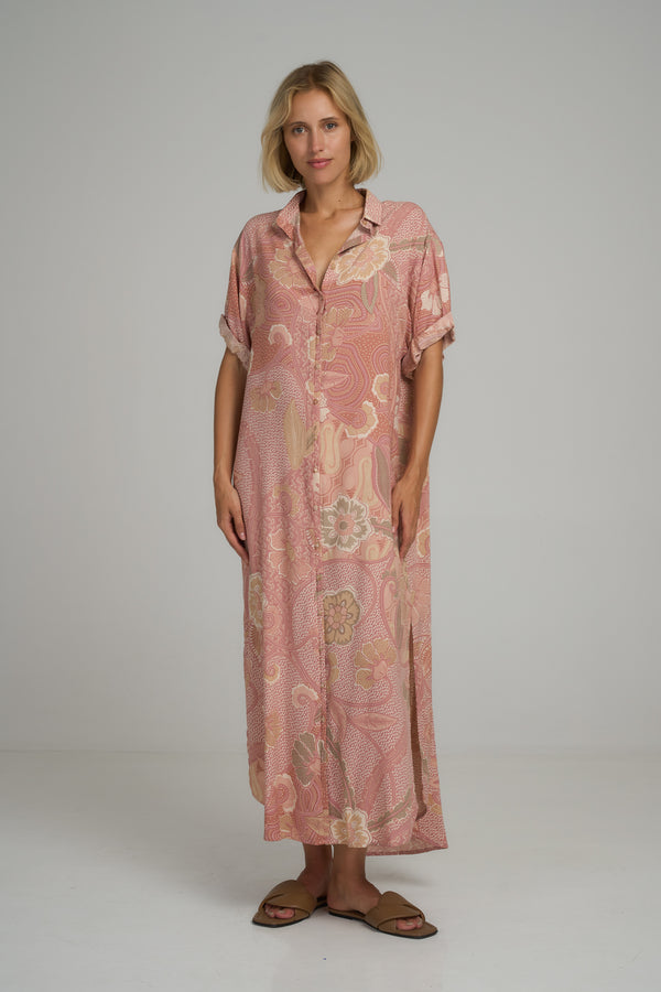 A model wearing a casual pink batik print maxi shirt dress by Lilya