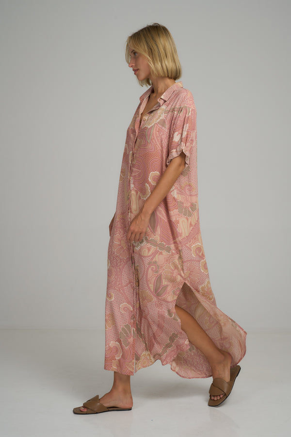 A woman wearing a pink floral maxi shirt dress by Lilya