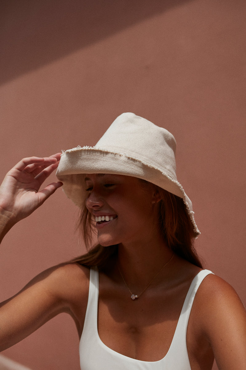 a women wearing white ivory canvas bucket hat by cove island essentials