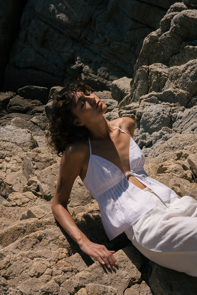 A model wearing a white cotton halter top leo top in ivory colour by lilya 