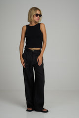 A woman wearing high rise black linen pants by Lilya