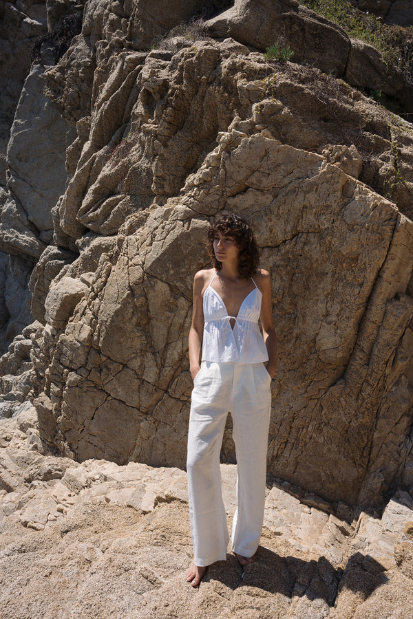 A model wearing white high rise linen pants by Lilya