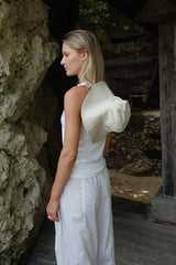 a girl standing back wearing white beach hat