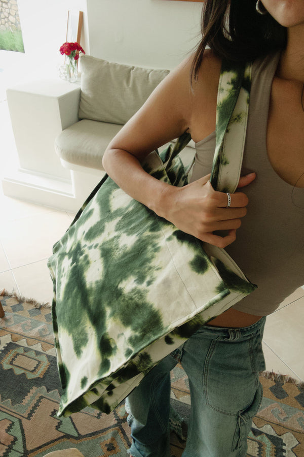 A woman holding a tie dye green bag