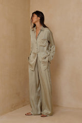 Model wears green satin shirt and pant set by LILYA