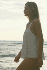 A side view of the Elodie lace cami styled with swim, worn on the beach