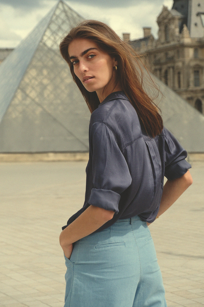 Model wears the LILYA soft rayon shirt in ocean tones tucked into light denim jeans.