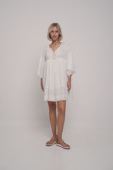 A model wearing a white mini summer dress by lilya in ivory colour