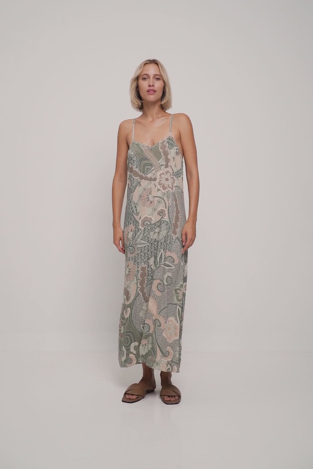 A woman wearing a low cut green summer batik floral dress by Lilya