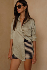 Model wears satin shirt with knit shorts as resort style outfit by LILYA.