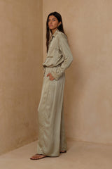 Side view of pants in green satin, worn as a silky set.